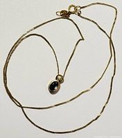 Full view of 10K yellow gold chain and pendant laid flat on white background