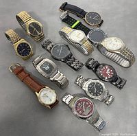 Photo showing all 12 men's wrist watches grouped together on a grey surface.