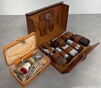 Smaller tan case open showing travel shaving kit contents including razor, brush, mirror.