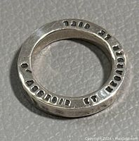 Top view of the sterling silver ring showing engraved text and markings around the circumference.