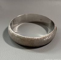 Front and side view of sterling silver sparkling textured bangle showing overall shape and texture.