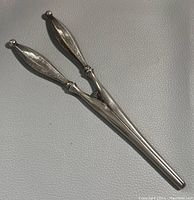Pair of silver handled antique glove stretchers laid on a textured surface, showing full length and shape.