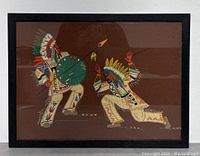 Full view of the framed Native American patchwork art showing two figures in traditional attire against brown background