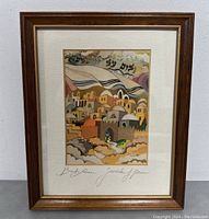 Front view of framed print showcasing colorful Jerusalem scene with Hebrew text and artist signature.