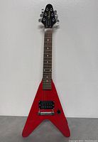 Full front view of red V-shaped travel guitar