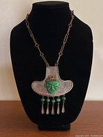 Full front view of the copper necklace displayed on a black bust, showing the pendant and chain.