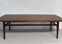 Front view of rectangular wooden coffee table with tapered legs and stretcher
