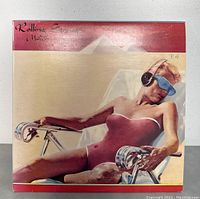 Front cover of the Rolling Stones 'Made In The Shade' vinyl record showing a woman reclining with headphones and sunglasses.