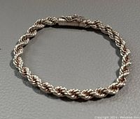 Full view of the solid silver twisted rope chain bracelet laid flat in a circular shape.