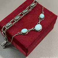 Necklace and bracelet displayed on red fabric box, showing turquoise stones and silver
