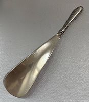 Top side of the vintage sterling handled shoe horn showing general shape and minor surface wear.