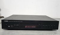 Front view of the Yamaha CD player showing the display and control buttons, CD tray closed.