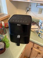 Black Ultima Omega air fryer showing front with handle and control panel.