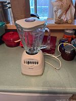 Photo showing an Oster blender with a glass jar and white base with speed control buttons on a countertop.