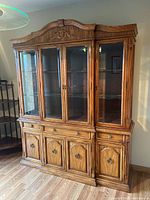 Front and angled view of wooden china cabinet showing glass doors, drawers, and storage compartments.