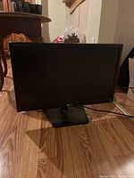 Front view of LG computer monitor on wooden floor, showing black bezel and stand.