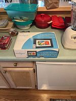 Boxed OmniTech digital photo frame on kitchen counter surrounded by various kitchen items like blender and containers.