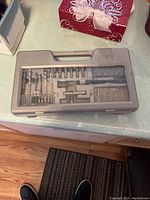 Closed view of grey plastic case containing assorted drill bits and screwdriver bits arranged internally.