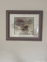 Photo of the framed picture on a wall showing a garden scene with flowers and a bench