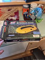 Photo showing unopened original box with printed image and details of the 2 person inflatable boat by H2O Sports.