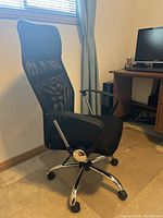 Side front angle showing the high mesh back with headrest, padded seat, armrest, and chrome base with wheels.