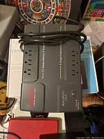 Top view of black APC Back-UPS ES 350 power bar showing 8 outlets, power cord, and labels for battery backup and surge protection.