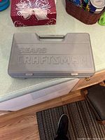Closed gray plastic Sears Craftsman ratchet set case on kitchen countertop.