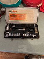 Open metal case showing the full 40 piece socket wrench set inside with various sockets, a ratchet wrench, and extension bars.