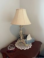 Table lamp on wooden side table with beige shade and decorative metal base