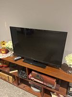 Seiki 33-inch TV on stand with remote and surroundings