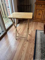 Side view of one wooden TV tray with folding metal legs showing height and structure.