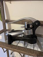 Photo of a lever style wine opener featuring a black and silver design with ergonomic handles.