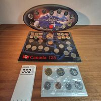 Overview of the three Canadian coin sets arranged on a table including Millennium 2000 quarter set, Canada 125 year quarter set, and Uncirculated 2000 coin set in blister pack.