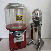 Side view of the Beaver gumball machine next to the Hamilton Beach milkshake mixer with the stainless steel cup inserted
