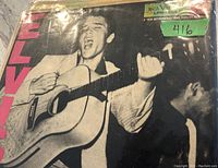 Front cover of the Elvis Presley 1956 debut mono LP record showing image of Elvis playing guitar and singing, with RCA Victor label in upper right corner.