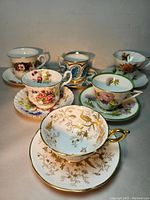 Photo showing all six fine china cups and saucers arranged together, highlighting varied floral and gold patterns.