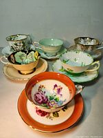 Photo showing all 6 fine china cups and saucers arranged in two rows, showcasing a variety of floral designs and colors.