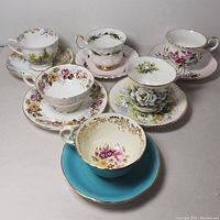Full set of six fine china cups and saucers with various floral and gold designs on table