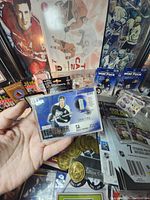 Close-up showing limited edition Vincent Lecavalier NHL player card numbered 094/150, with various coins, card packs, and memorabilia in background
