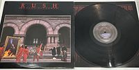 Front cover of the Rush Moving Pictures LP showing workers carrying framed paintings and two men in conversation on steps of stone building.