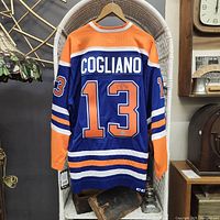 Back view of blue and orange Edmonton Oilers jersey showing 'COGLIANO' name and number '13' with autograph on the '3'.