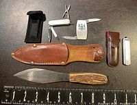 Full overview of all items including throwing knife, sheath, and three pocket knives.