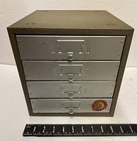 Front view of entire cabinet showing four drawers with labels and pulls, and a measuring scale for size reference.