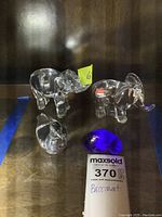 Four crystal items on wood shelf: two elephants, one bird dish, one blue shell dish