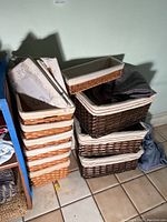 Stack of five light natural wicker baskets with white fabric liners, some linens on top, showing condition and size.