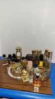 Wide shot showing a collection of 17 assorted small fragrance bottles arranged on a tabletop and circular tray