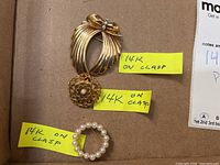 Three pins on cardboard with yellow notes indicating '14k on clasp'