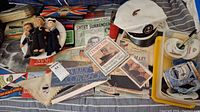 Full overview of the Queen Mary memorabilia with dolls, books, hats, postcards, and collectibles spread on a plaid fabric surface.