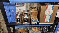Photo of shelf with various Olympic collectibles including boxes, boxes with figurines, Disney plate, and comic books.