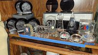 Shelf view showing assorted Olympic plaques, glass trophies and paperweights